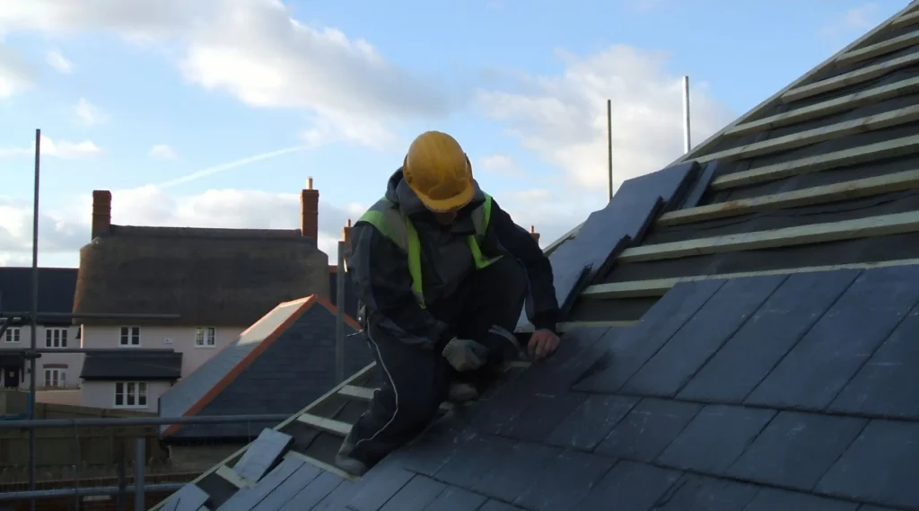 Roofer installing slate tiles on pitched roof