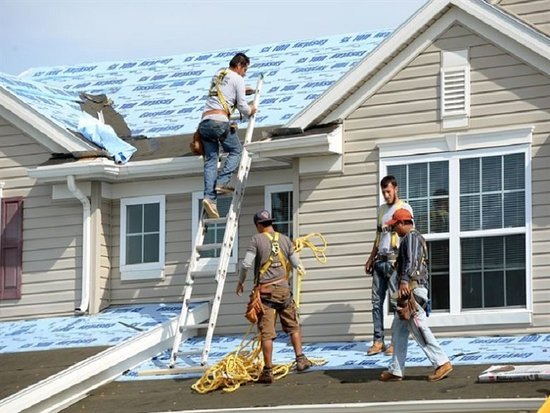 Roofers installing underlayment on a house roof